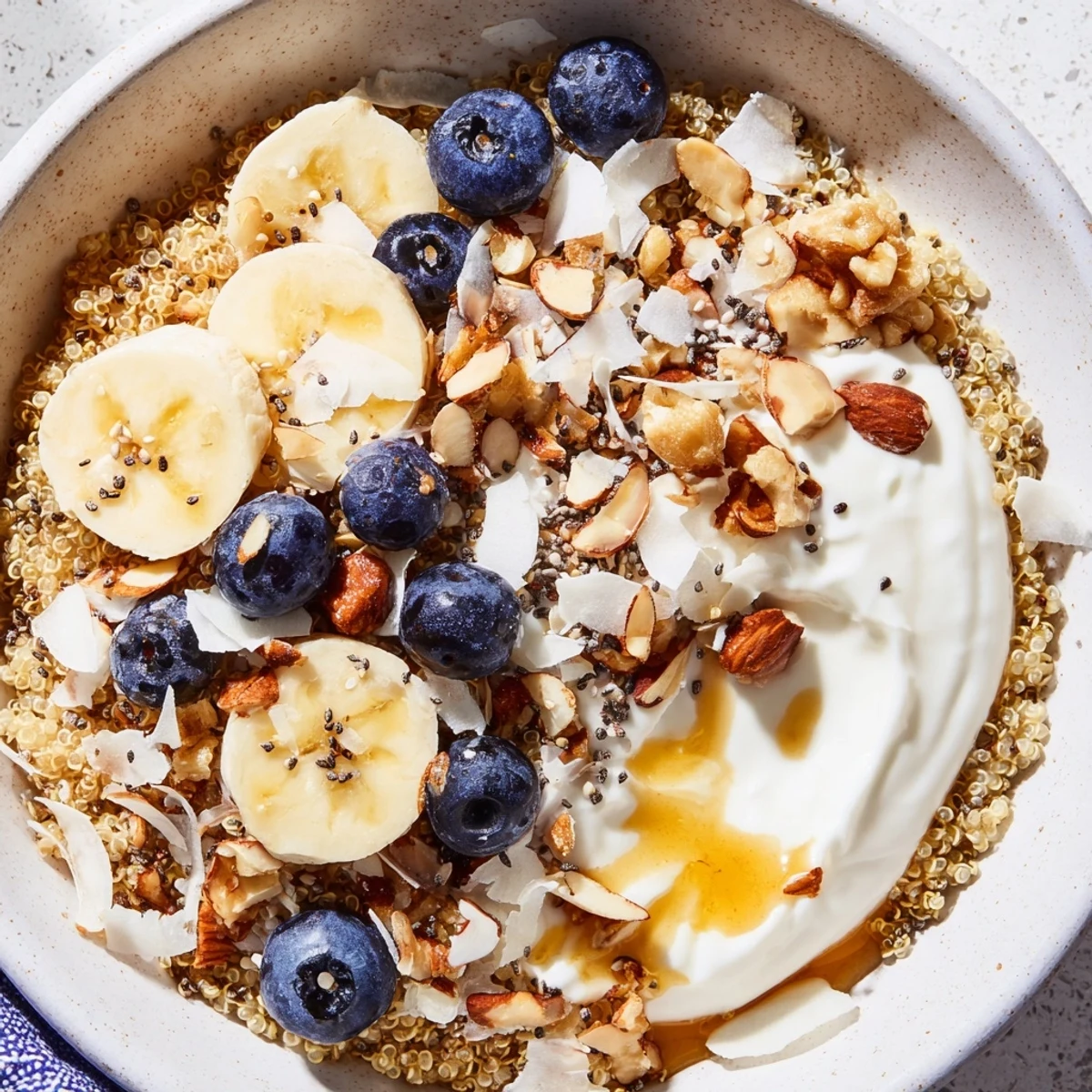 Protein-packed blueberry quinoa breakfast bowl drizzled with maple syrup and sprinkled with shredded coconut
