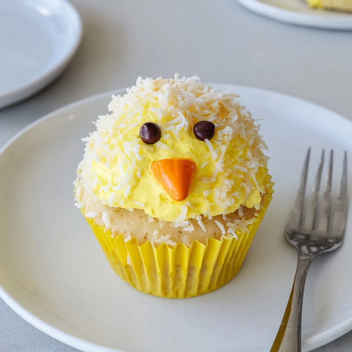 Adorable Easter Chick Cupcakes with fluffy yellow frosting and candy faces on white serving platter