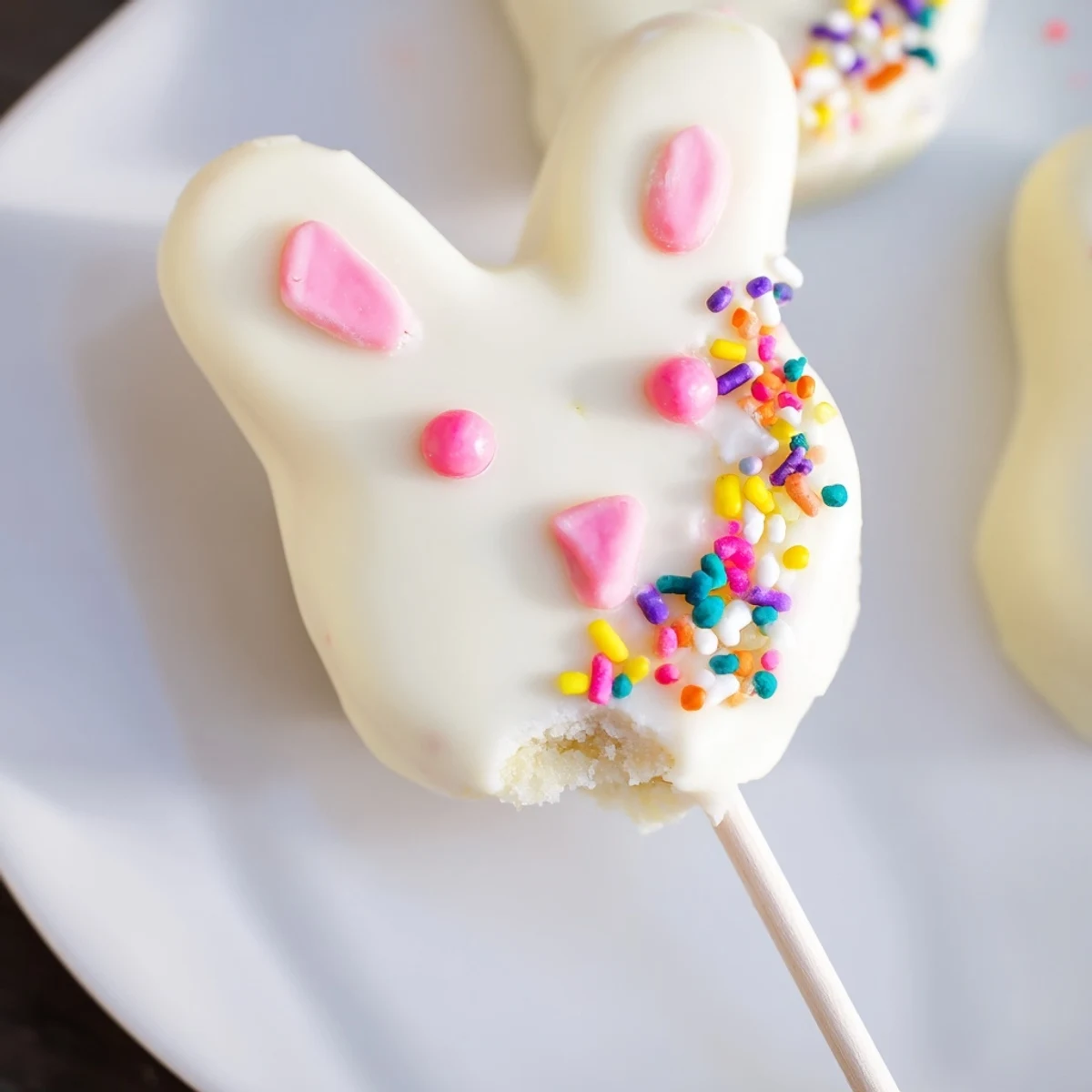 Adorable white chocolate bunny cakesicles with candy eyes and pink ears on sticks