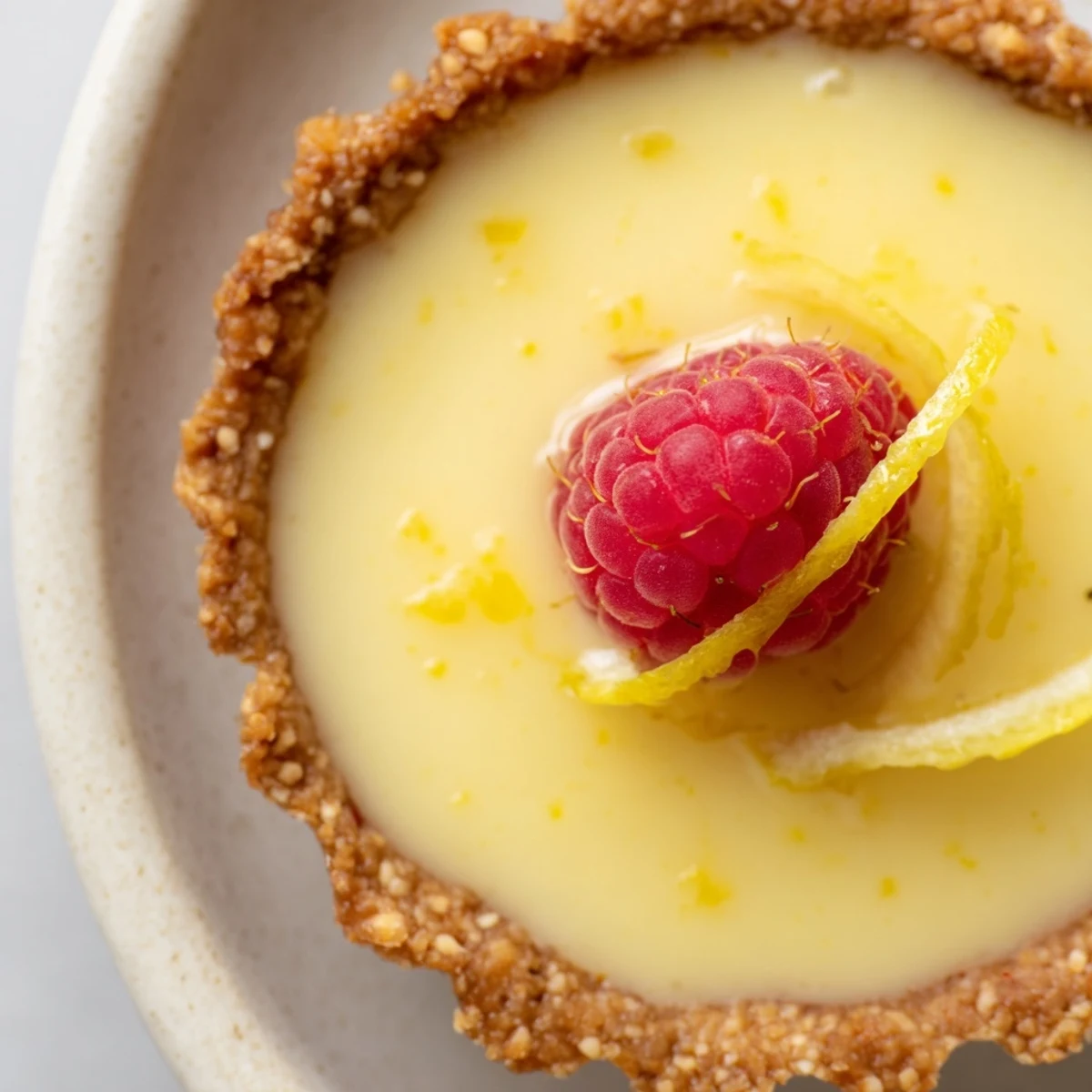 Creamy vegan lemon tarts in crisp almond crusts garnished with delicate lemon zest