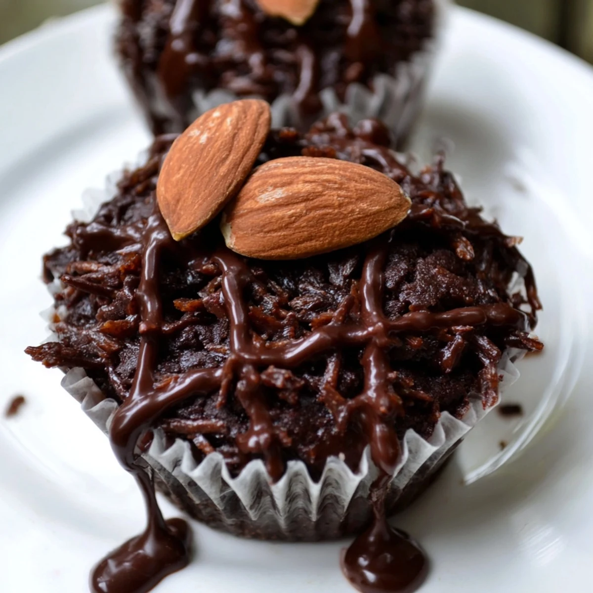 Rich Flourless Almond Joy Cupcakes drizzled with melted chocolate and topped with roasted almonds
