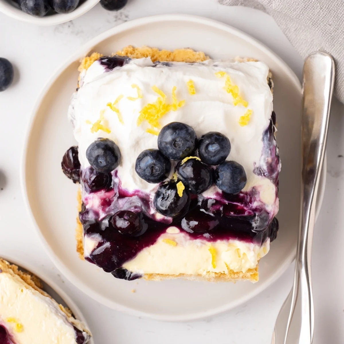 Tall slices of lemon blueberry lasagna with purple berry swirls and fluffy cream