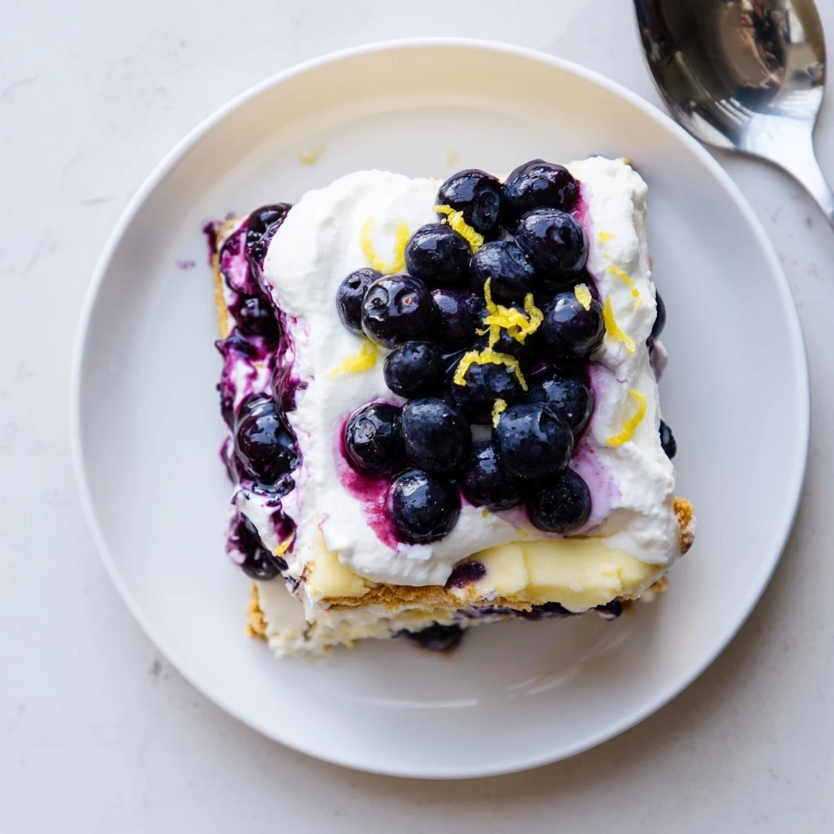 Creamy lemon blueberry lasagna dessert served on a white plate with zest garnish