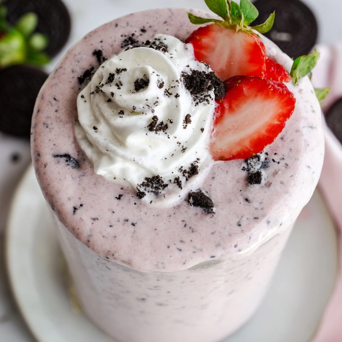 Thick pink strawberry Oreo milkshake topped with whipped cream and cookie crumbs