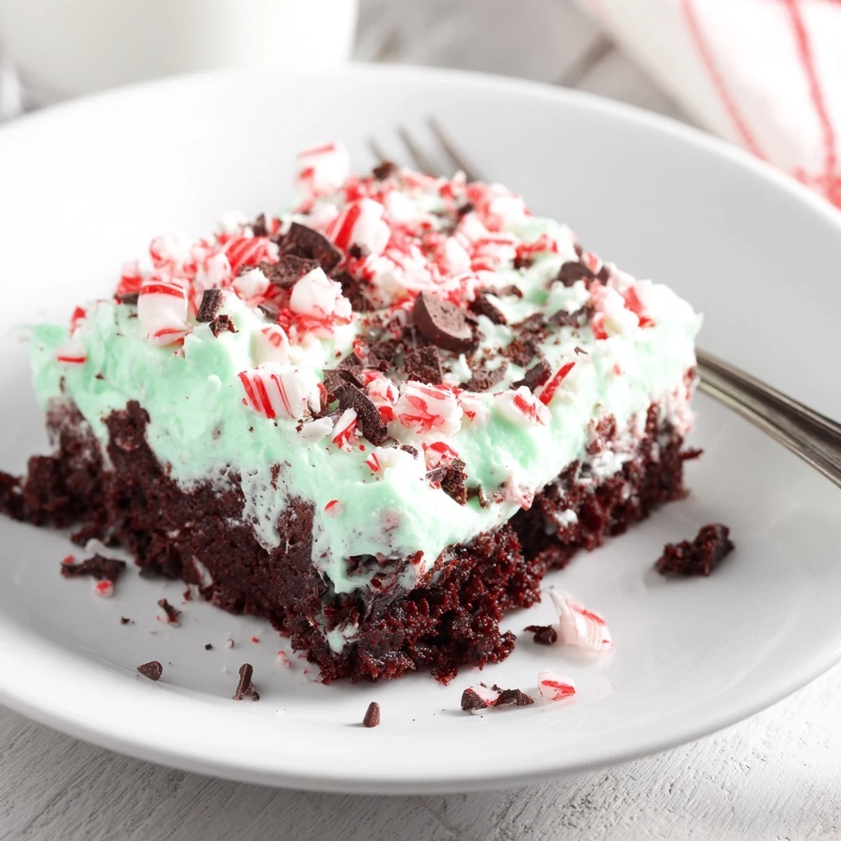 Peppermint Poke Cake with fluffy whipped topping and crushed peppermint candies
