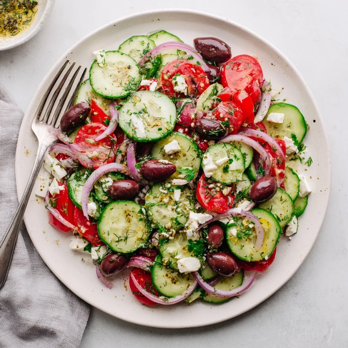 Colorful Mediterranean cucumber salad featuring sliced cucumbers, red onions, and fresh herbs in glass bowl