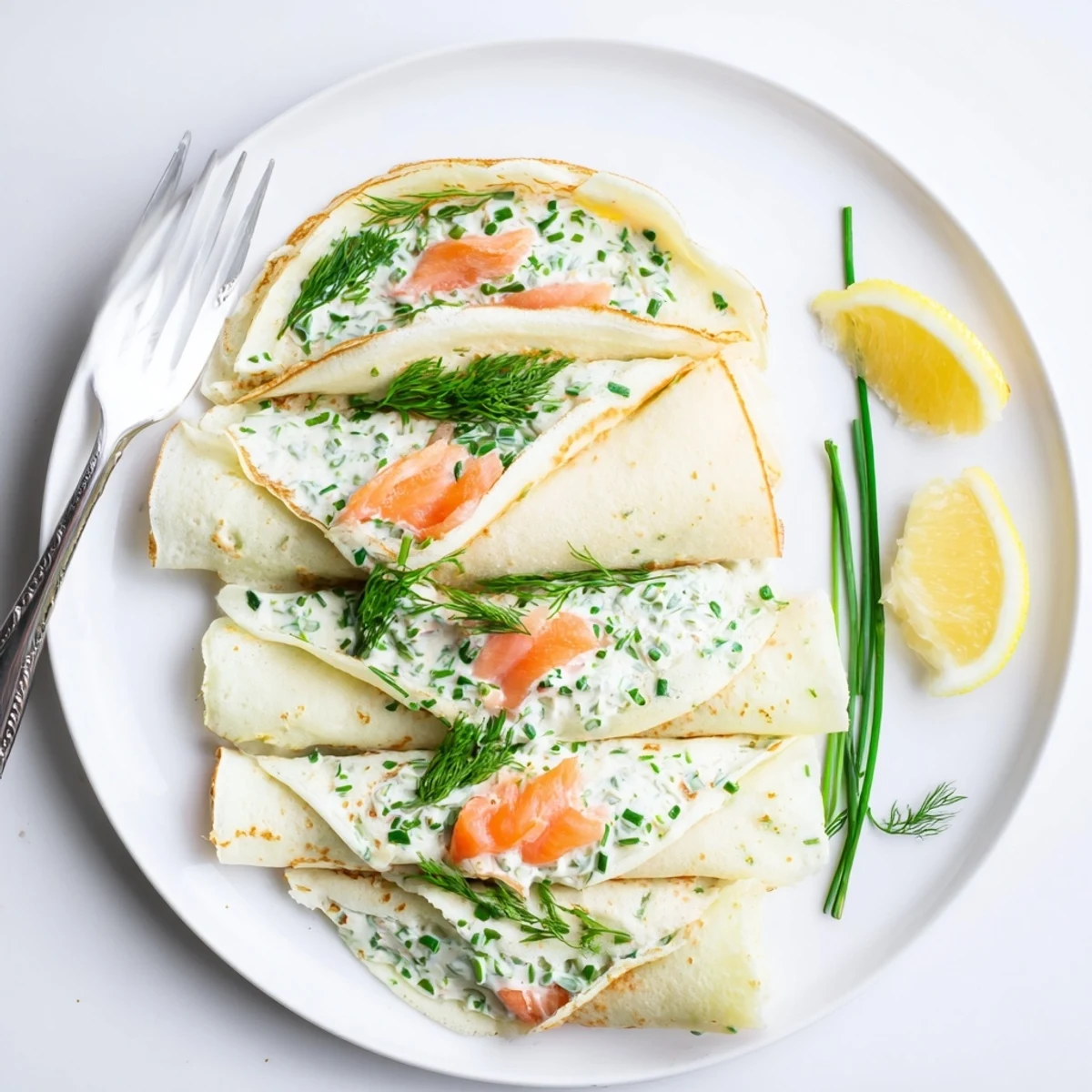 French brunch dish featuring thin crepes wrapped around silky smoked salmon and fresh dill