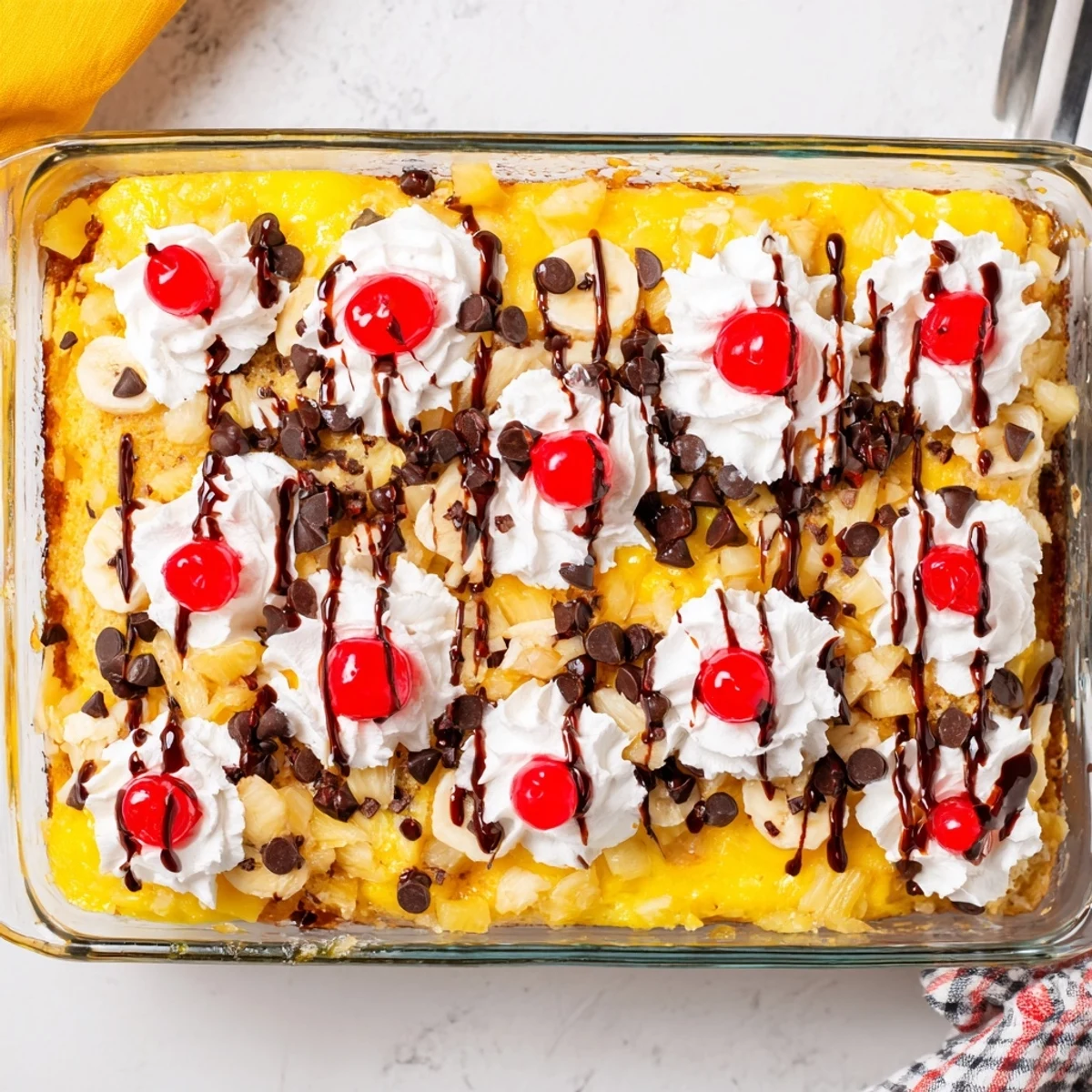 Decadent banana split dump cake drizzled with chocolate syrup and garnished with fresh fruit