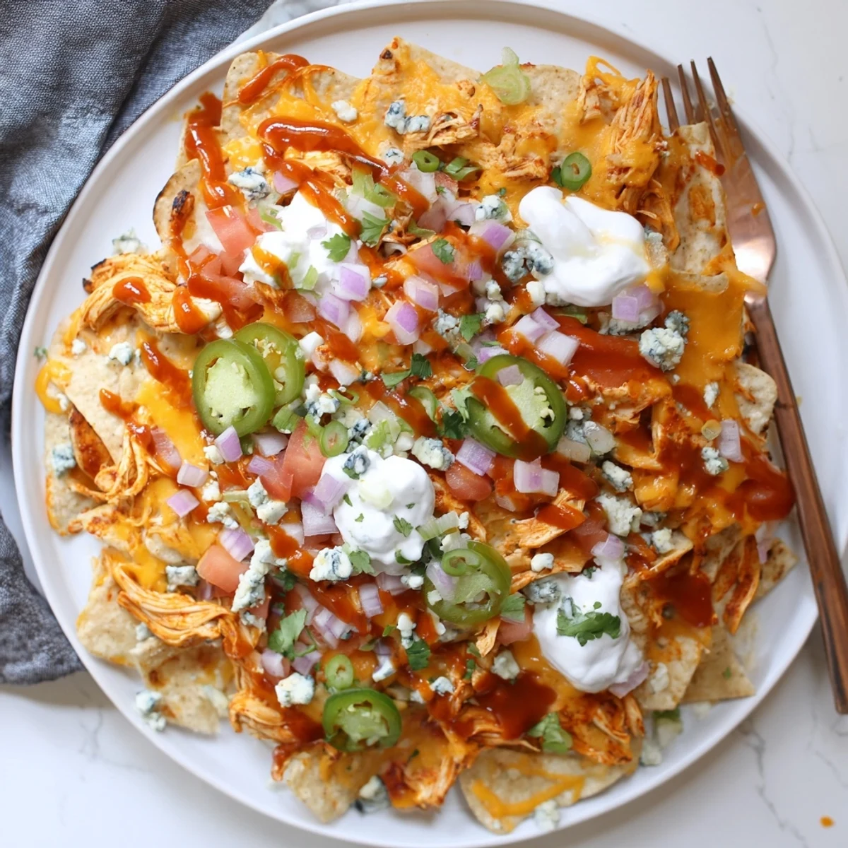Buffalo Chicken Nachos piled with melty cheddar, spicy sauce, and fresh cilantro