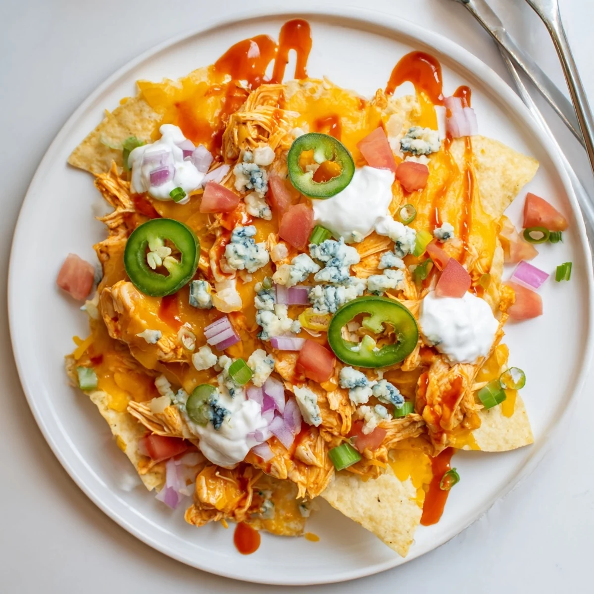 Game-day Buffalo Chicken Nachos served hot with sour cream and green onions