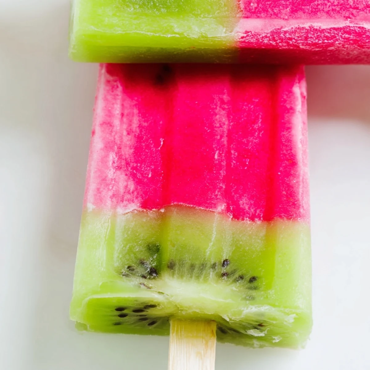 Watermelon kiwi fruit pops feature vibrant pink and green layered frozen treats on wooden sticks
