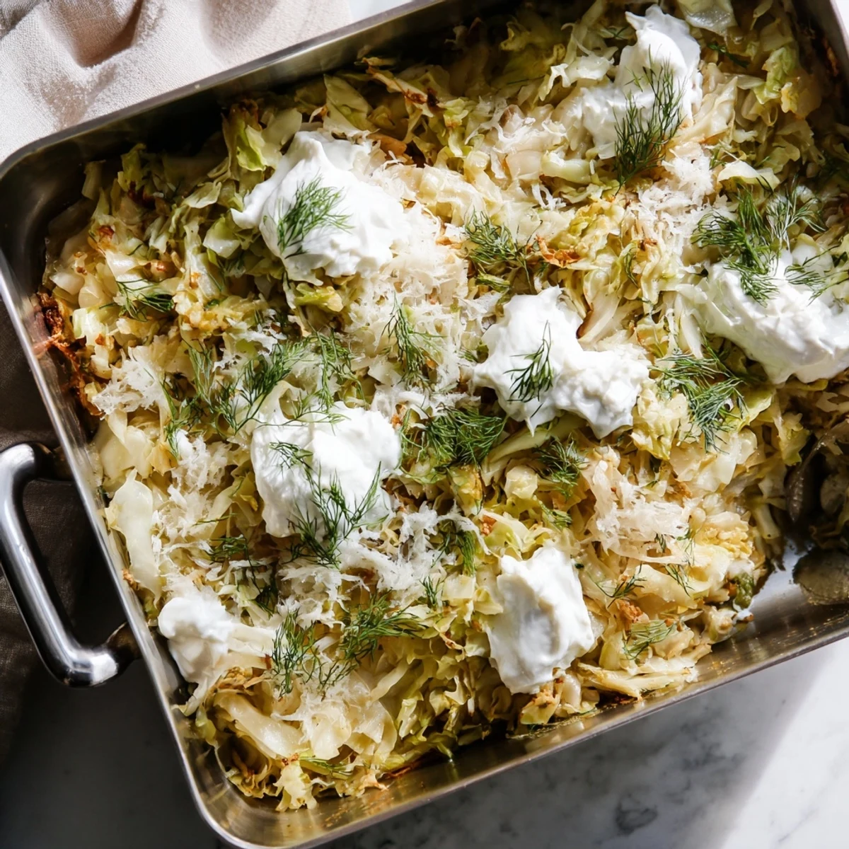 Golden slow roasted cabbage and sauerkraut casserole bubbling in a baking dish with fresh dill garnish