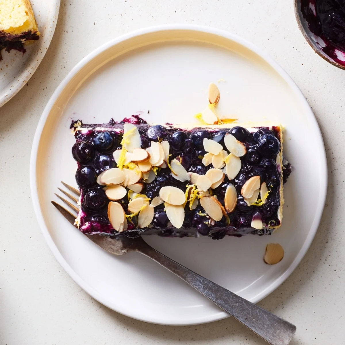 Lemon Blueberry Poke Cake With Almond Topping, glossy sauce filling moist pockets.