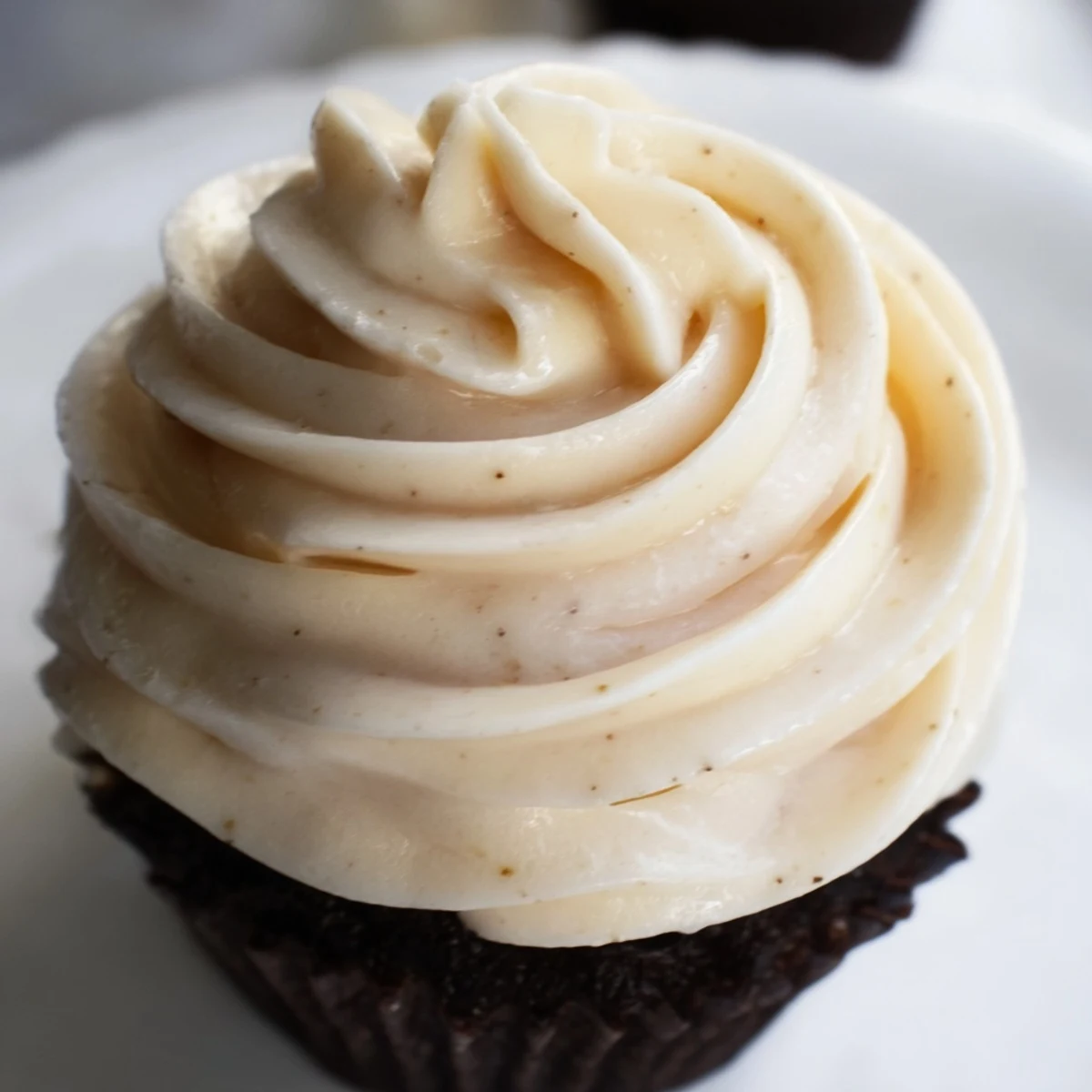 Silky Italian meringue buttercream spread smoothly over a freshly baked cupcake