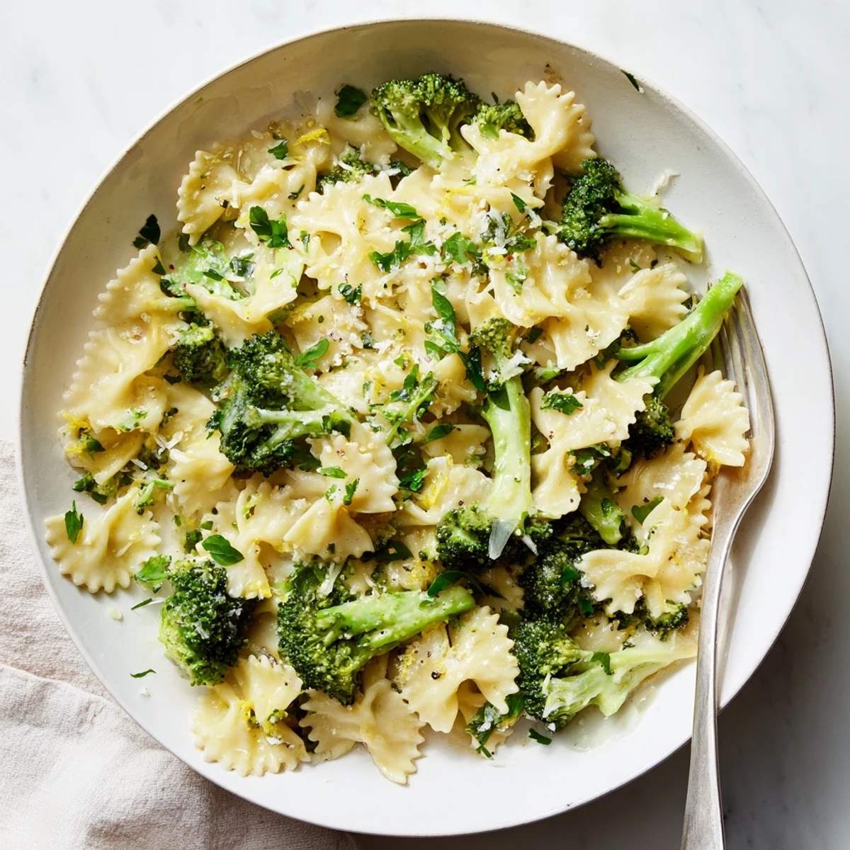 Curly mafaldine pasta coated in creamy lemon sauce with vibrant broccoli and Parmesan