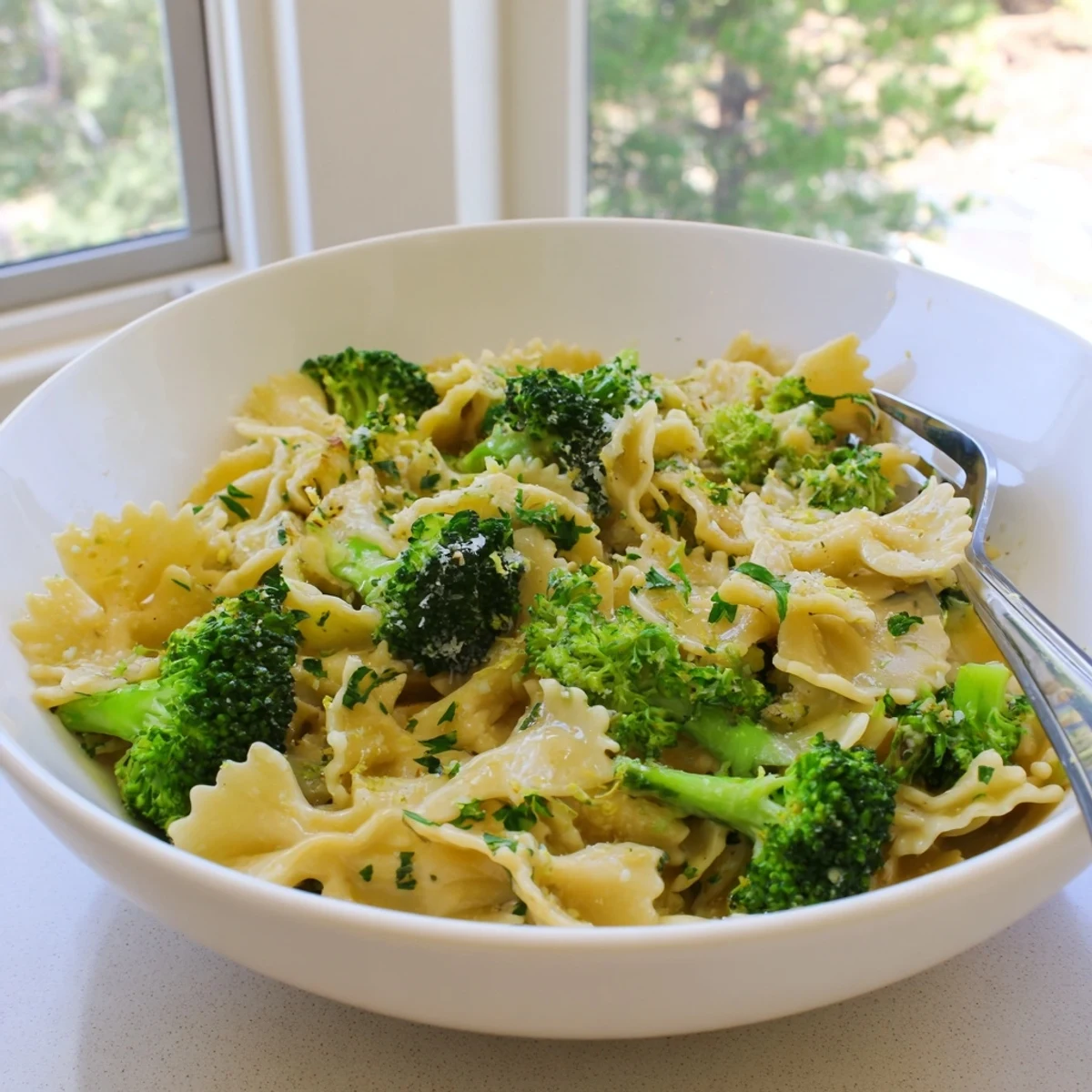 Steaming plate of Mafaldine Pasta Limone Broccoli finished with fresh herbs and shaved cheese