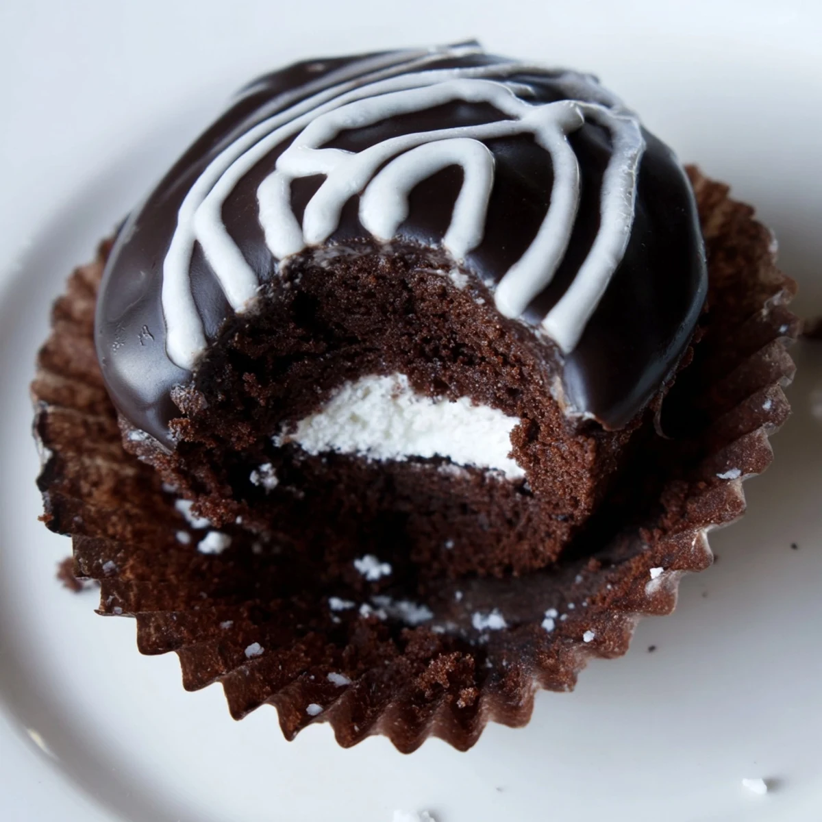 Homemade Hostess Cupcakes with glossy chocolate ganache and piped white icing swirls