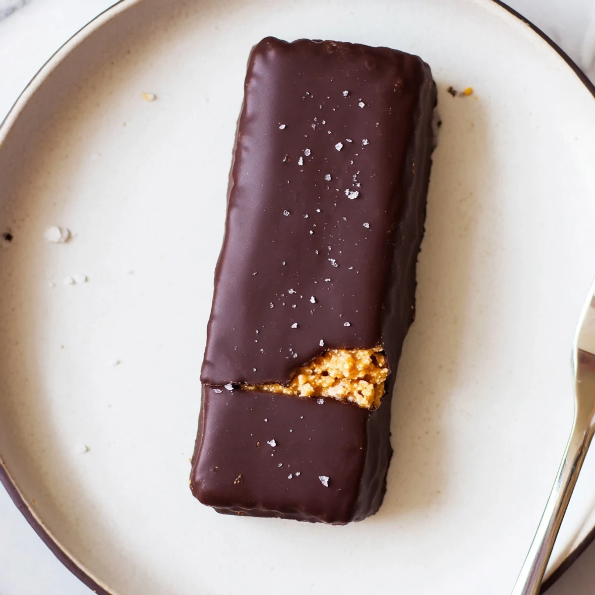 Crunchy healthy homemade Butterfingers dipped in glossy dark chocolate on a parchment-lined tray